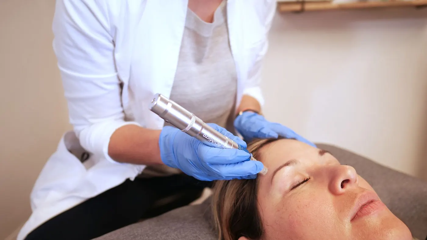 Therapist at Aarogita using a handheld therapy device during a facial session